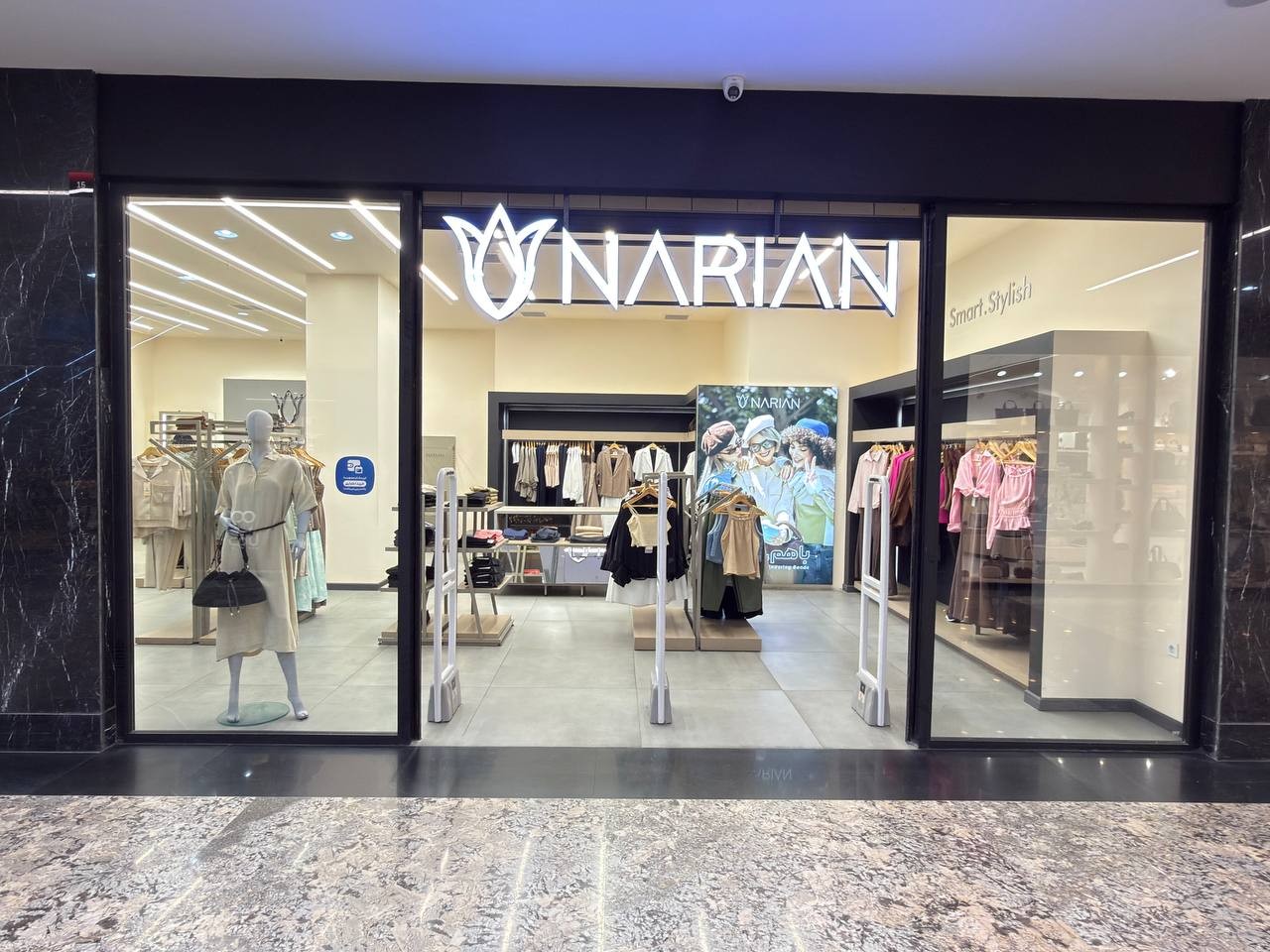 Photograph of a Narian branch from the mall corridor: the lit logo above a glass front, with mannequins and racks inside
